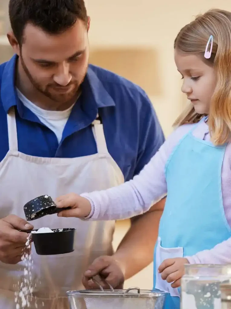 Dad and daughter measuring flour together while baking at home in the kitchen