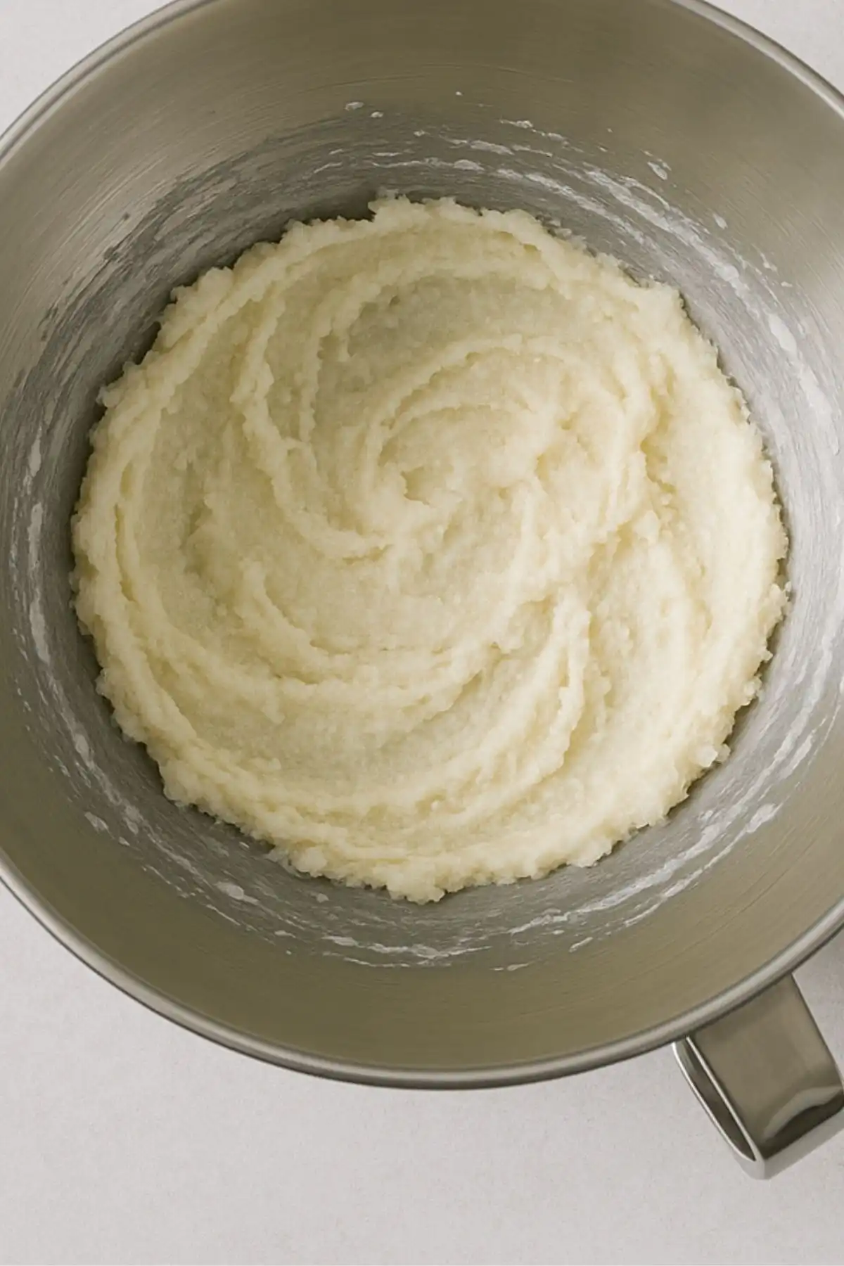 Creamed butter and sugar in a stainless steel mixing bowl, swirled and fluffy