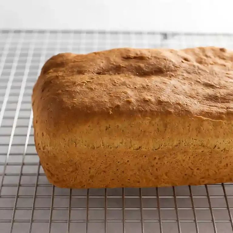 Golden-brown loaf of gluten-free and sugar-free bread resting on a wire cooling rack